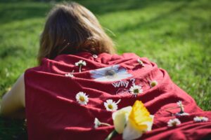 赤いセーターの上に花をのせた女性